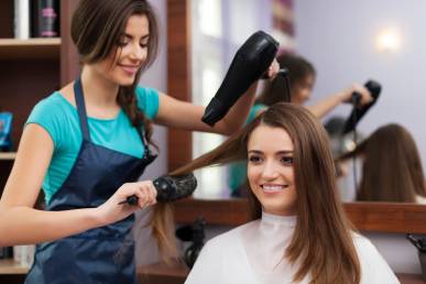 female hairdresser using hairbrush hair dryer 1